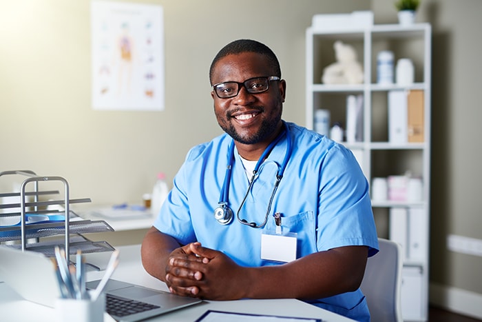 Young clinician in uniform sitting at workplace